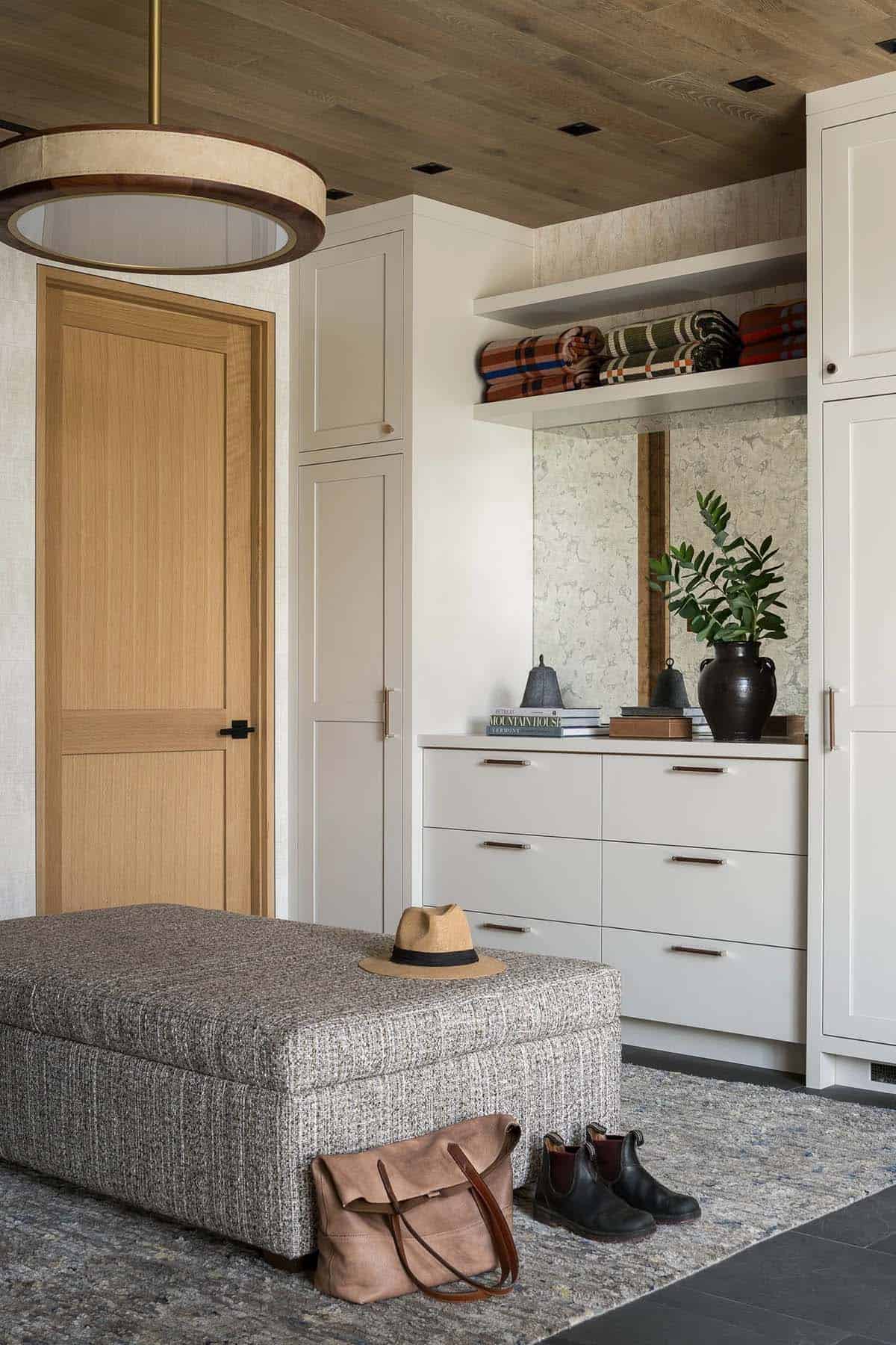 Mudroom with upholstered bench, white cabinetry, and plaid blankets