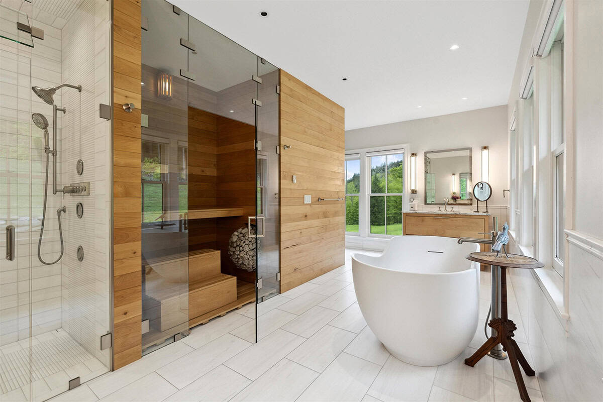 Primary bathroom with a glass shower, cedar sauna, and freestanding tub on white tile floors