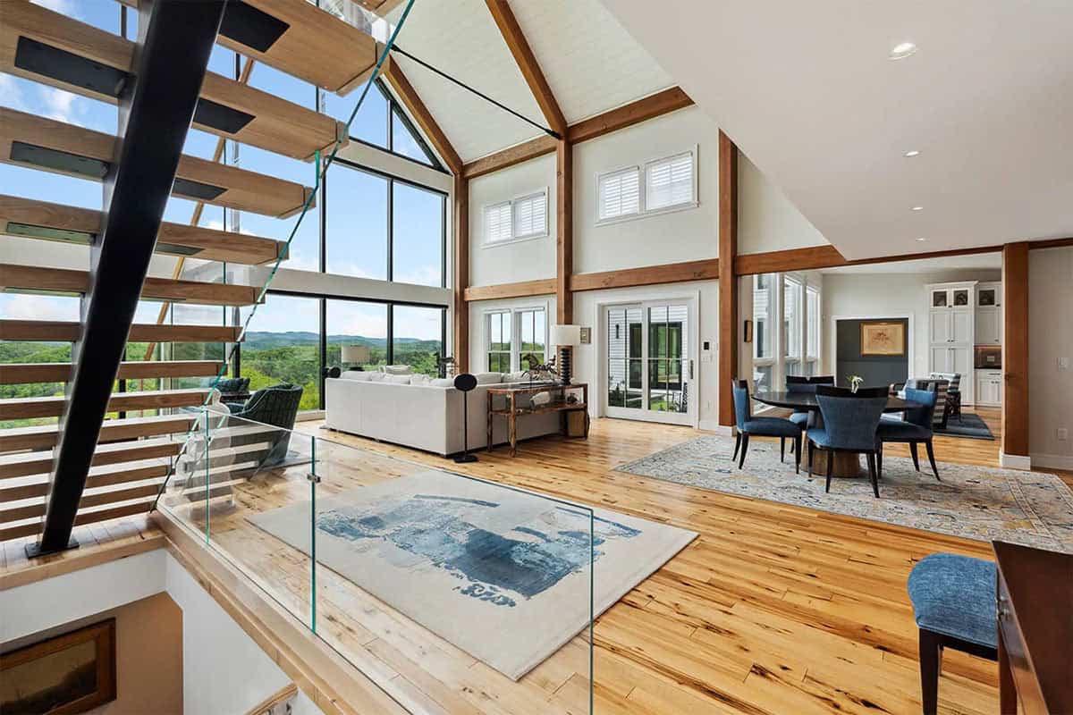 View from the floating staircase over a glass railing into the great room and dining area