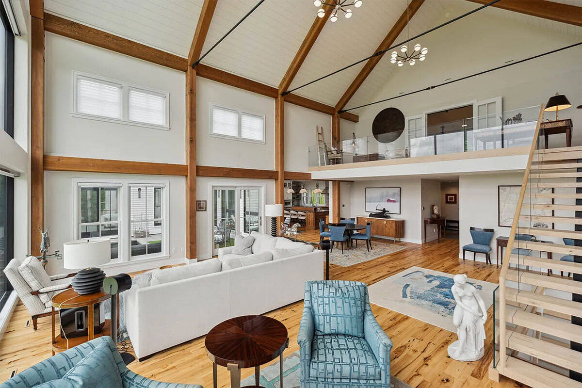 Great room looking toward the dining area and kitchen beneath a glass-railed loft, with a marble statue by the stairs