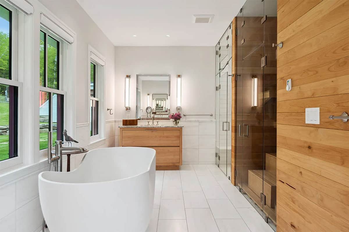 Primary bathroom with a freestanding tub by the windows, wood vanity, glass steam shower, and cedar sauna