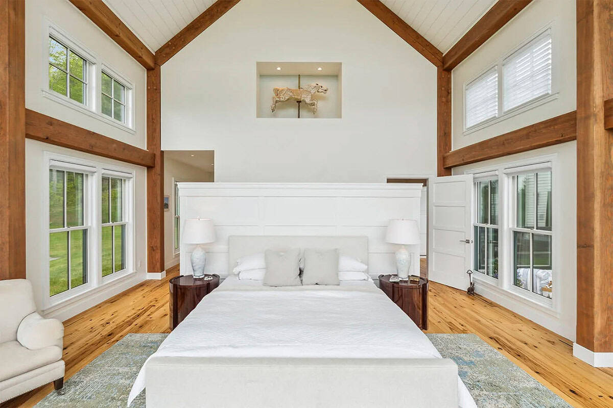 Primary bedroom with a paneled half-wall behind the bed and a carousel horse displayed in a niche above