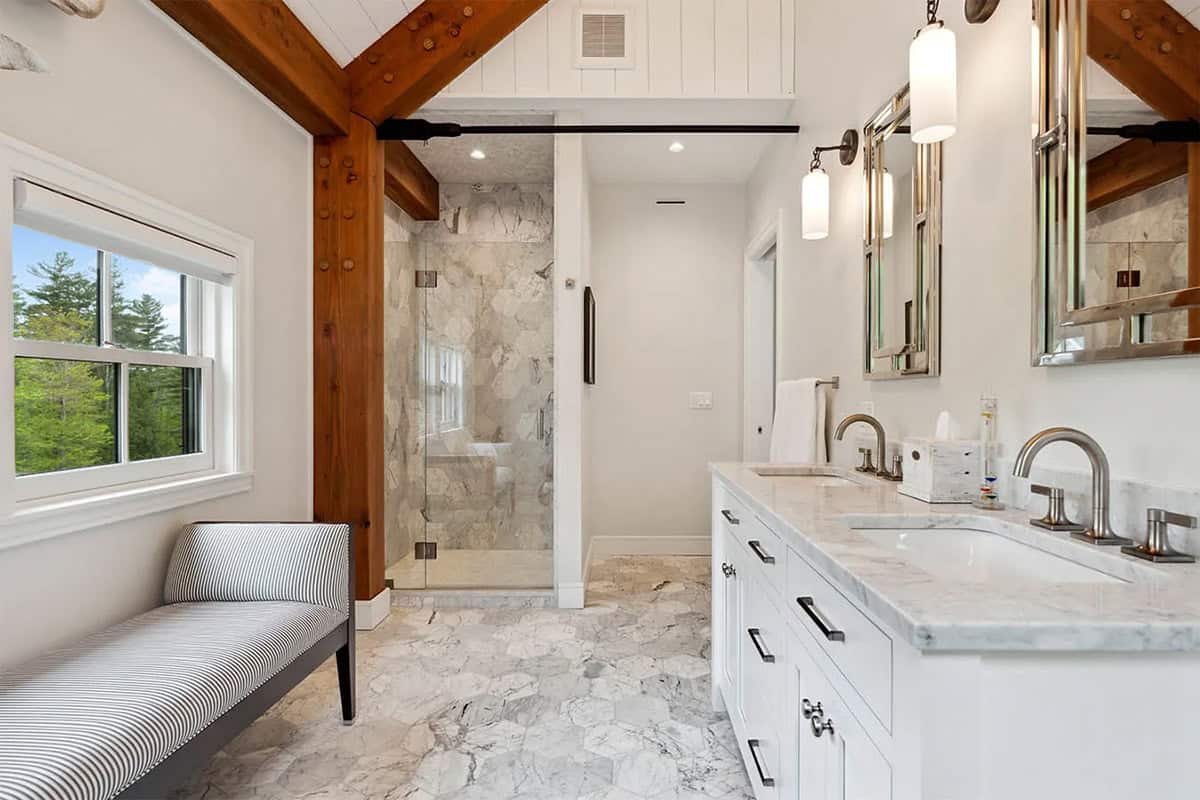 Bathroom with a marble hexagon floor, white double vanity, glass shower, timber framing, and a striped bench