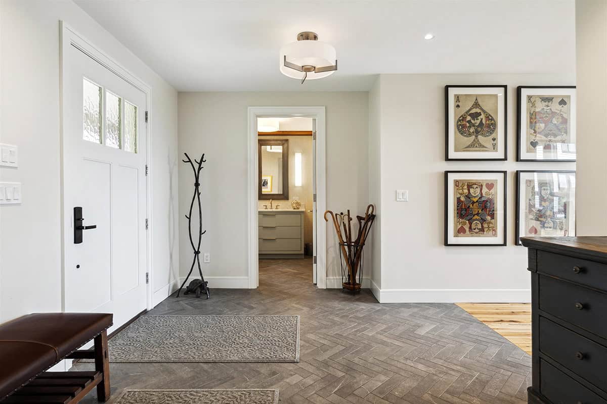 Entry with a herringbone stone floor, framed playing card artwork, and a doorway to the powder room