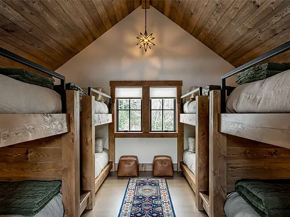 Bunk room with four built-in timber bunk beds beneath a wood-plank gable ceiling with a star pendant light