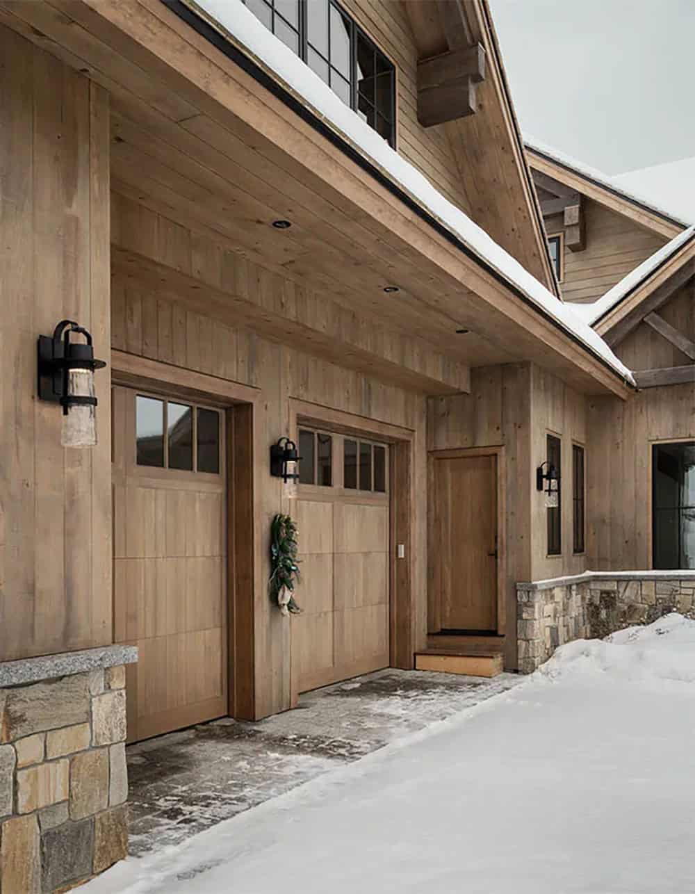 Two-car garage with wood carriage-style doors, lantern sconces and a side entry door under a covered overhang