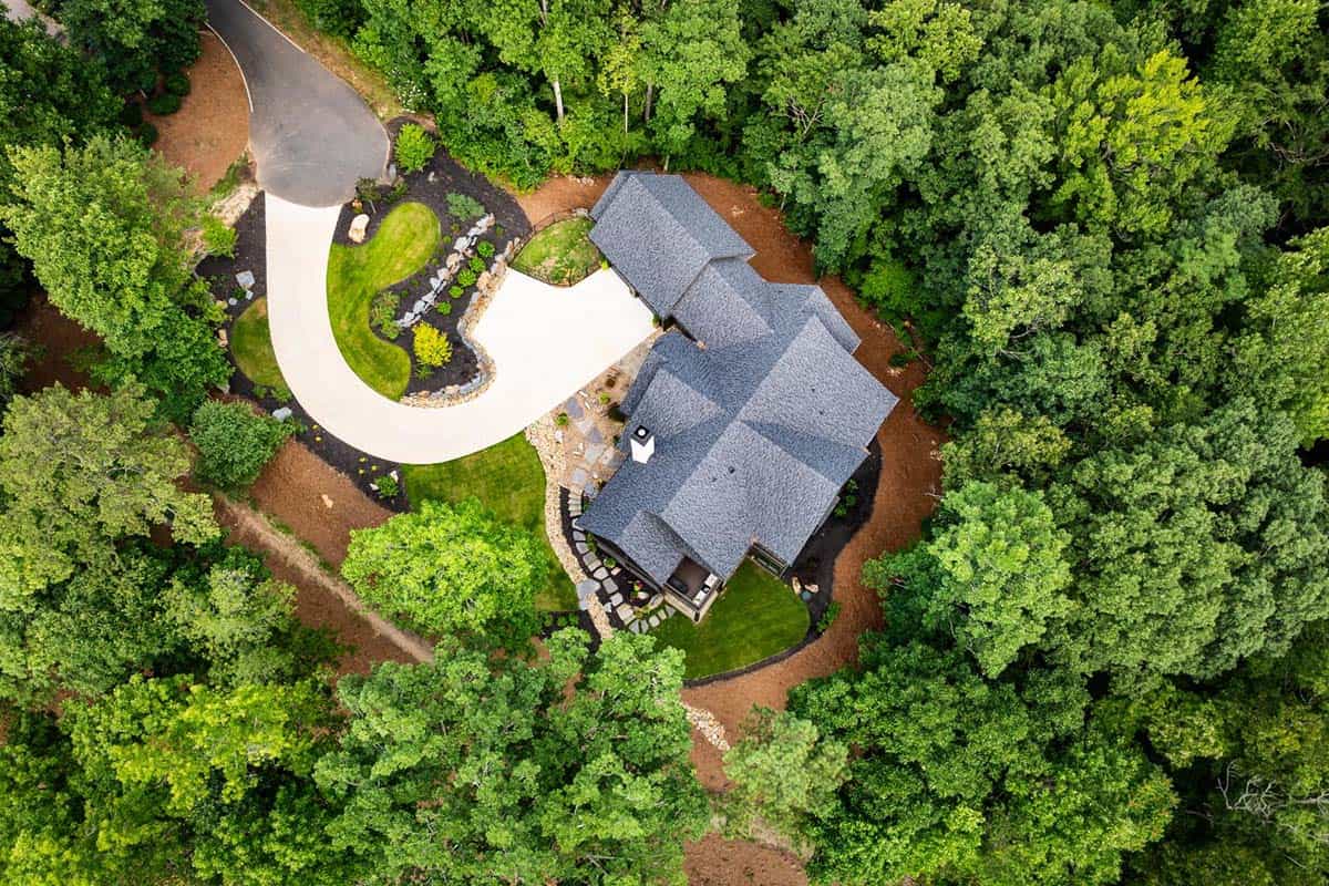 Overhead aerial view of home and curved concrete driveway in the woods