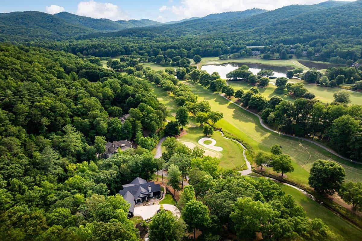 Aerial view of home beside a golf course with mountains in the distance