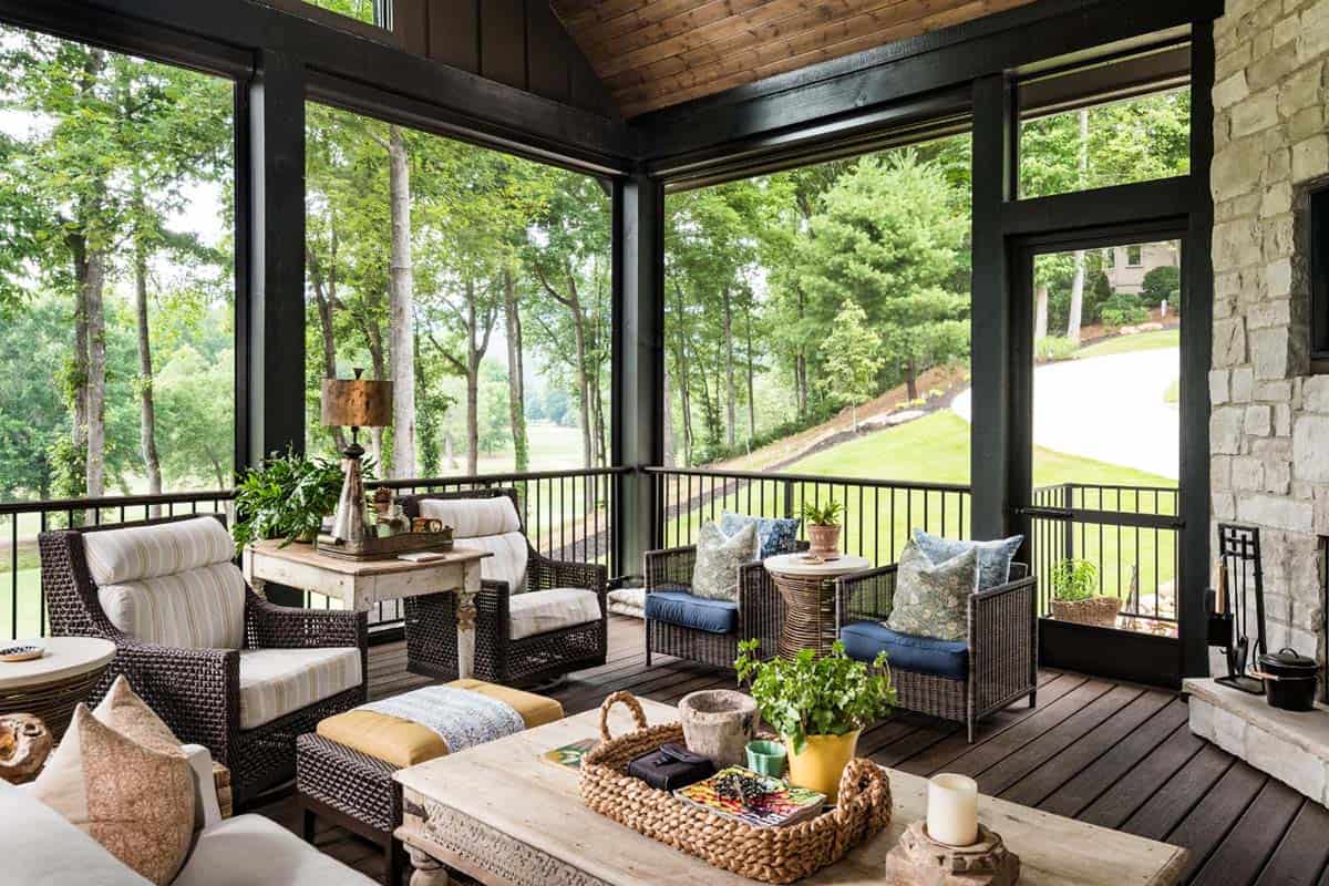 Screened porch with wicker seating, wood ceiling and stone fireplace