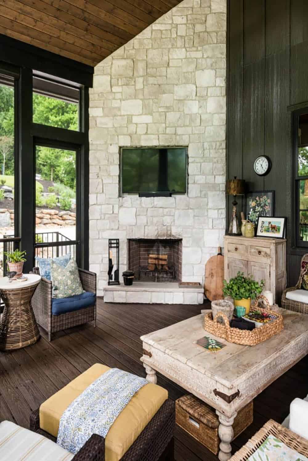 Tall white stone porch fireplace with TV and dark board-and-batten wall