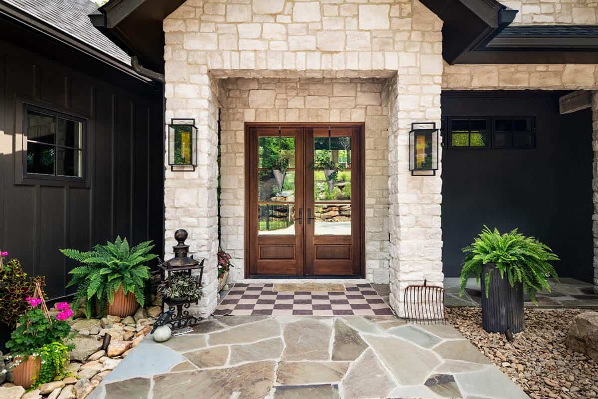 Wood double front doors framed by white stone with checkered doormat