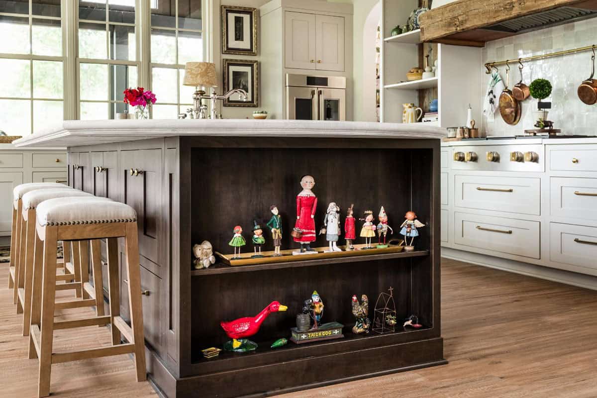 Dark wood kitchen island with open shelf displaying folk art figurines