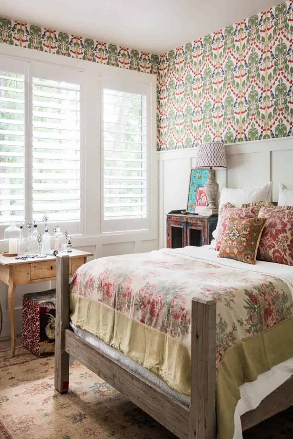 Guest bedroom with bird and cherry wallpaper, rustic wood bed and floral bedding