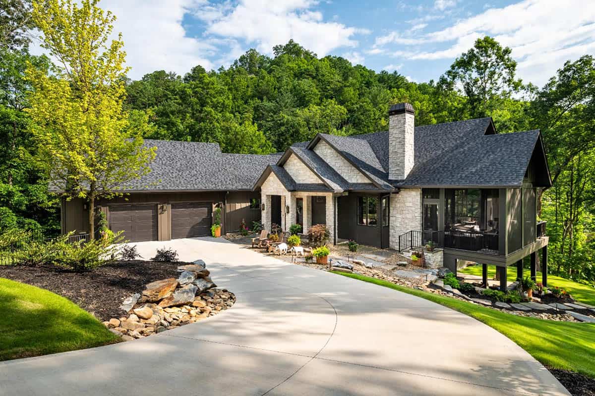Exterior of stone home with screened porch on posts and curved driveway