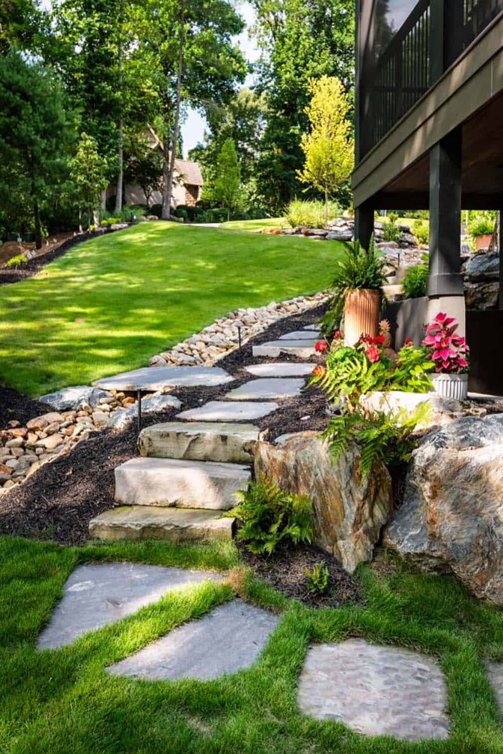 Stone steps and flagstone path beside landscaped lawn and porch