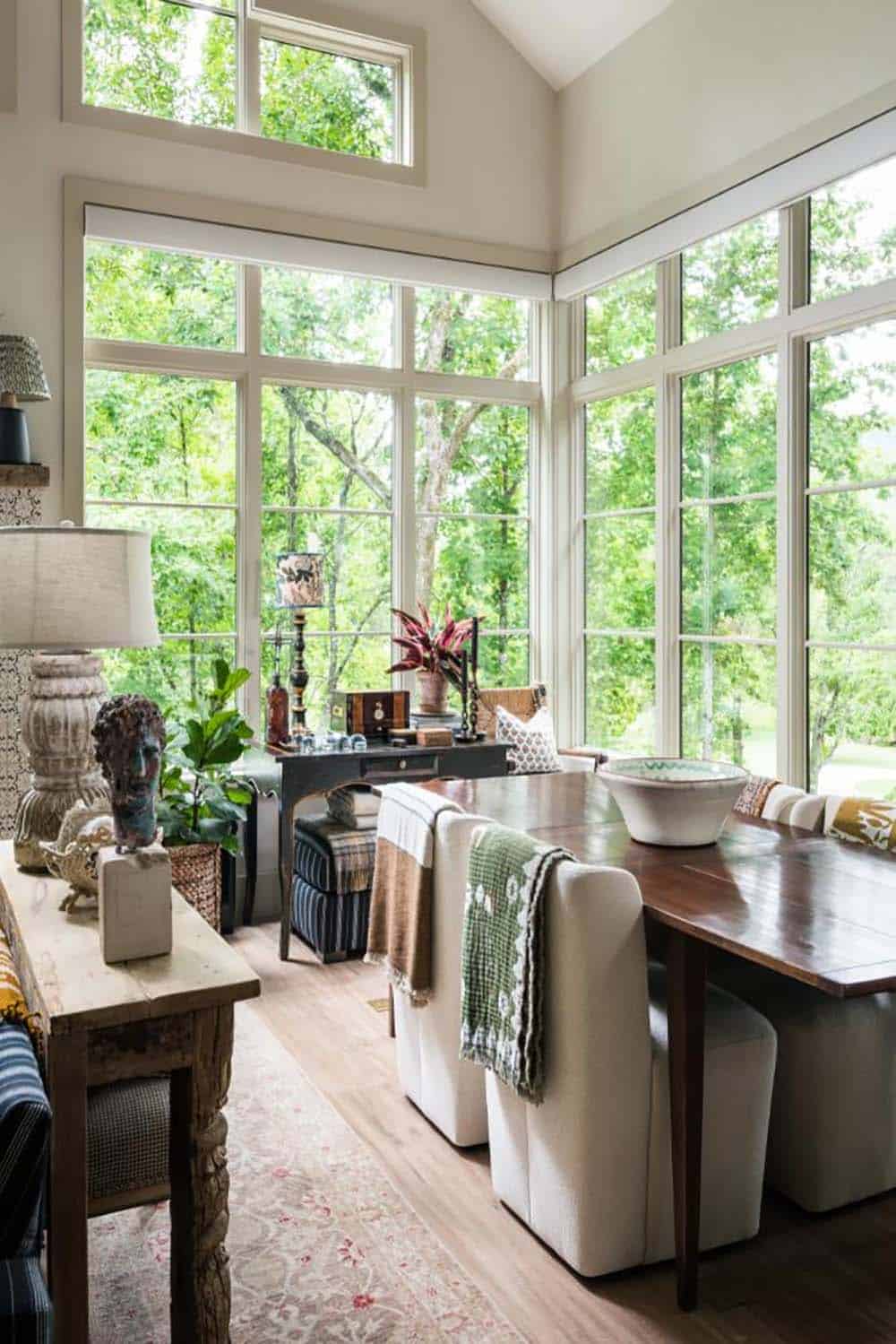 Dining area with tall corner windows, wood table and upholstered chairs