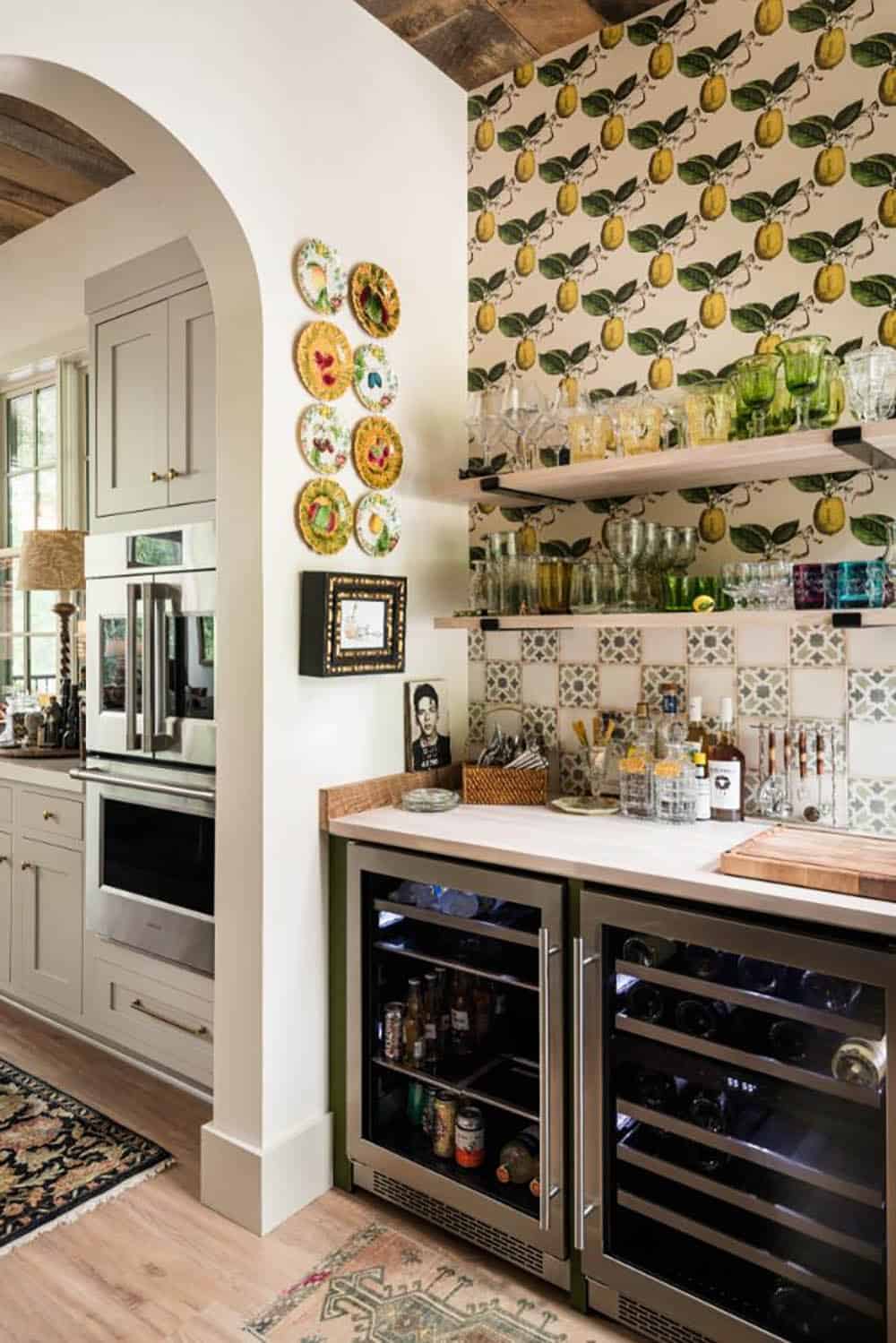 Wet bar with lemon wallpaper, open shelves and wine refrigerators by an arch