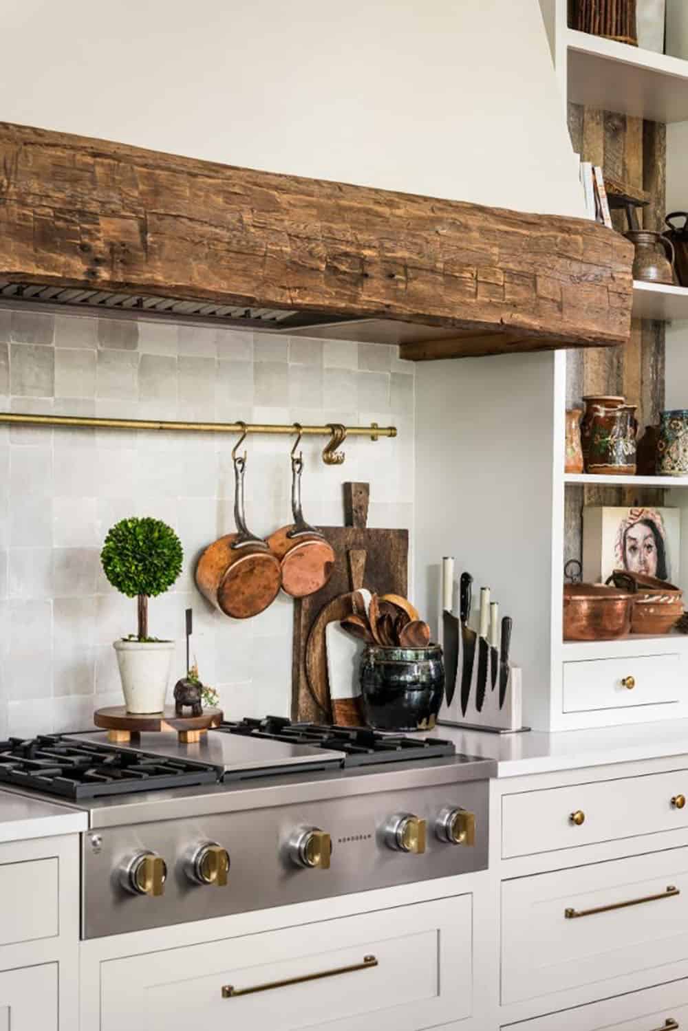 Range wall with reclaimed wood beam on plaster hood and copper pots