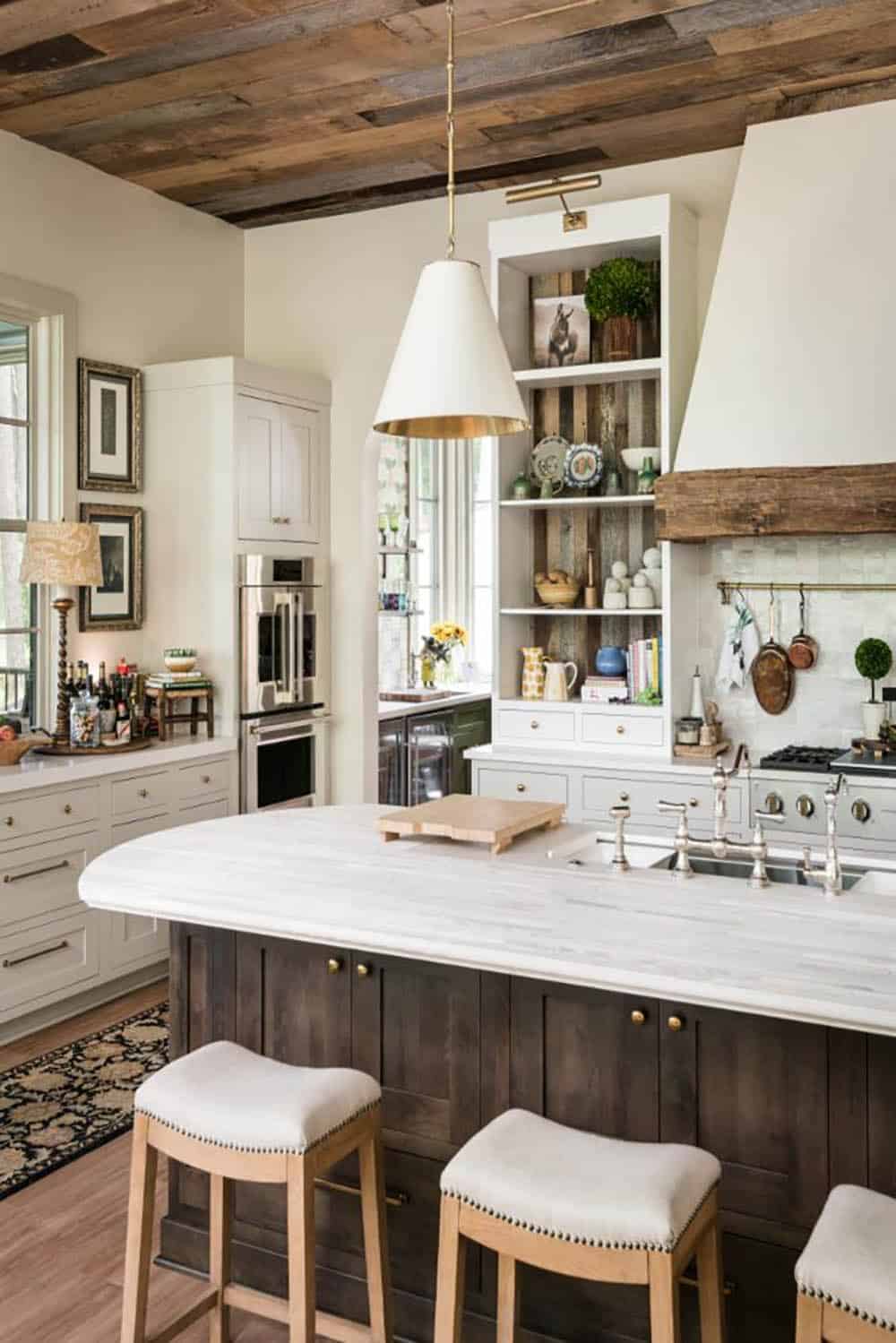 Kitchen island with white pendant and view to wall ovens