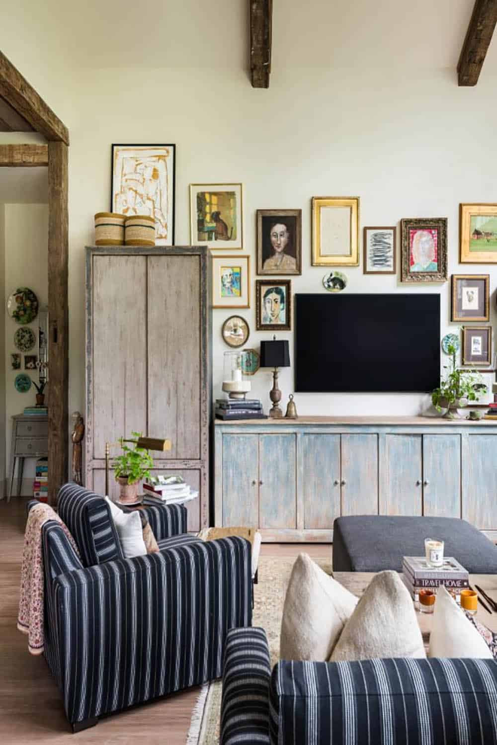 Great room with gallery wall, distressed armoire and striped armchair