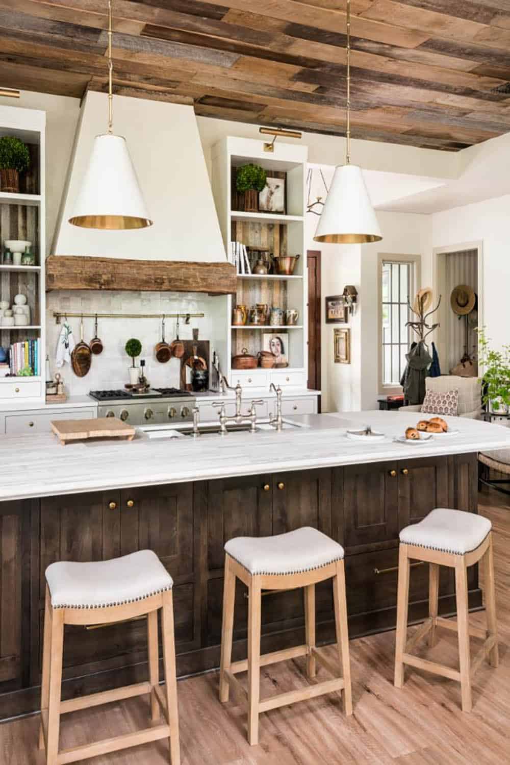 Kitchen island with three stools under white cone pendants