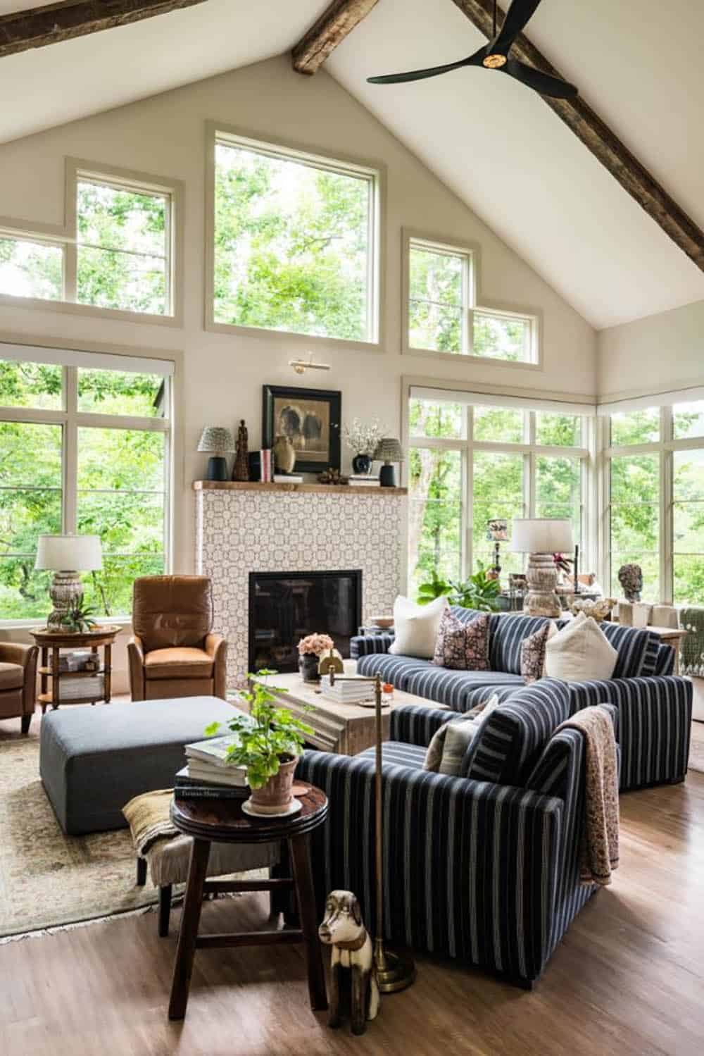 Vaulted great room with exposed beams, tall windows and striped sofas