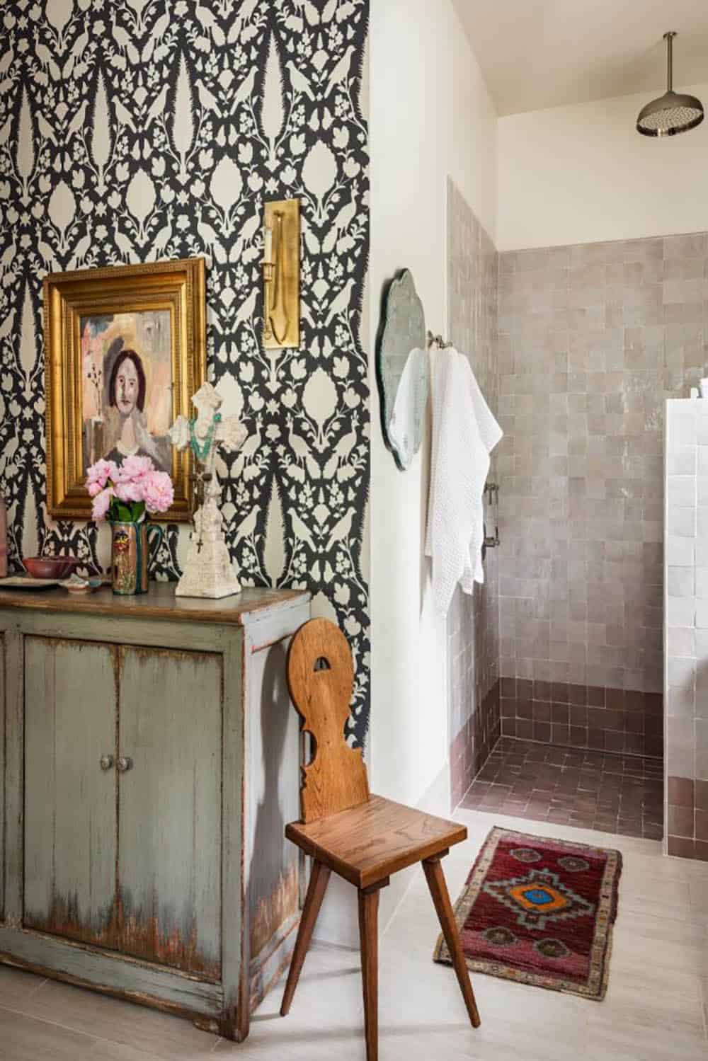 Primary bathroom with distressed green cabinet, wood chair and walk-in shower