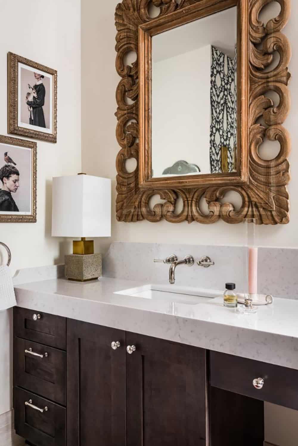 Bathroom vanity with carved wood mirror and wall-mounted faucet
