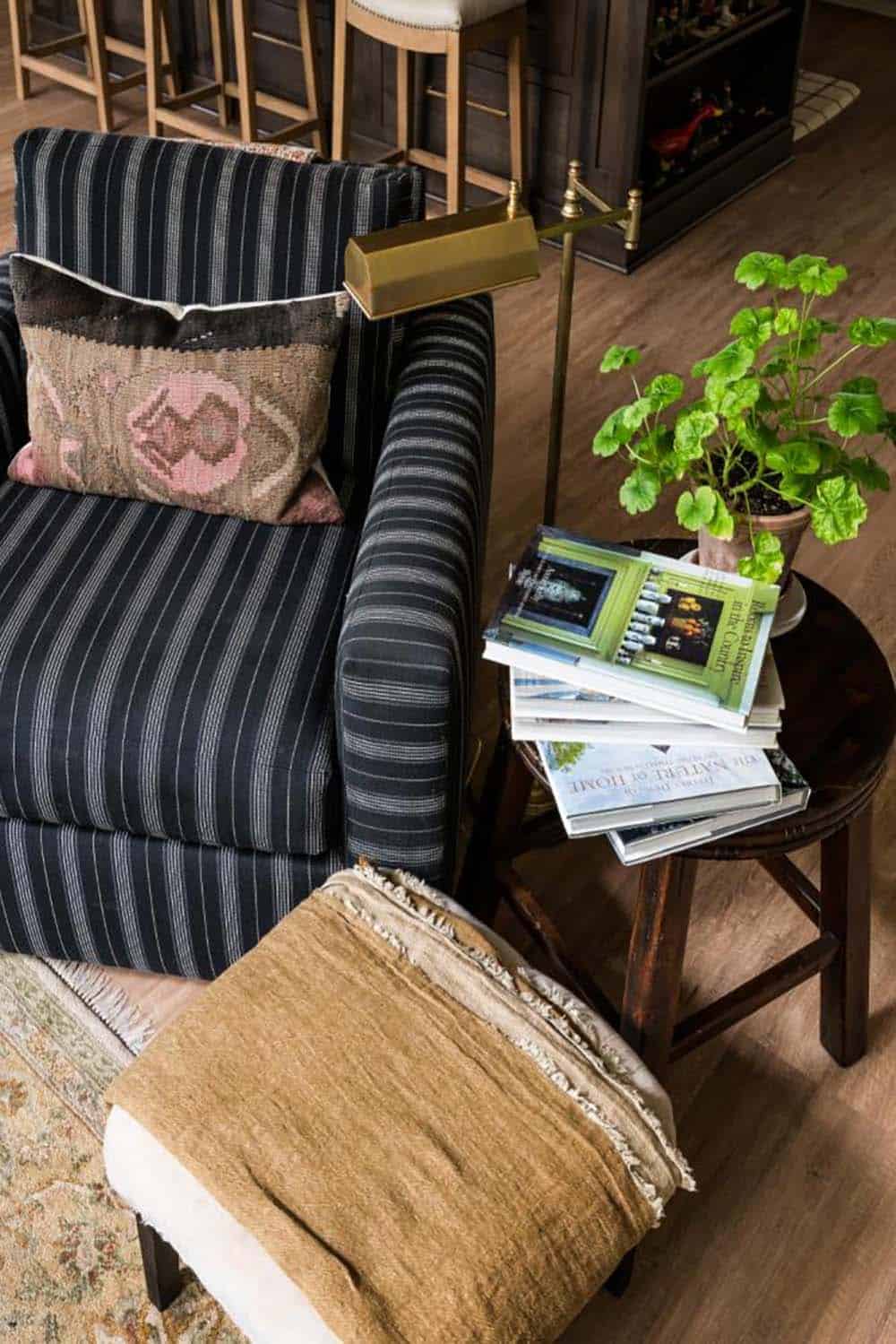Striped armchair with brass floor lamp and books on wood side table