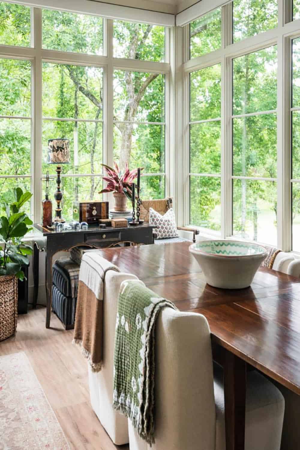 Dining table with upholstered chairs before floor-to-ceiling windows