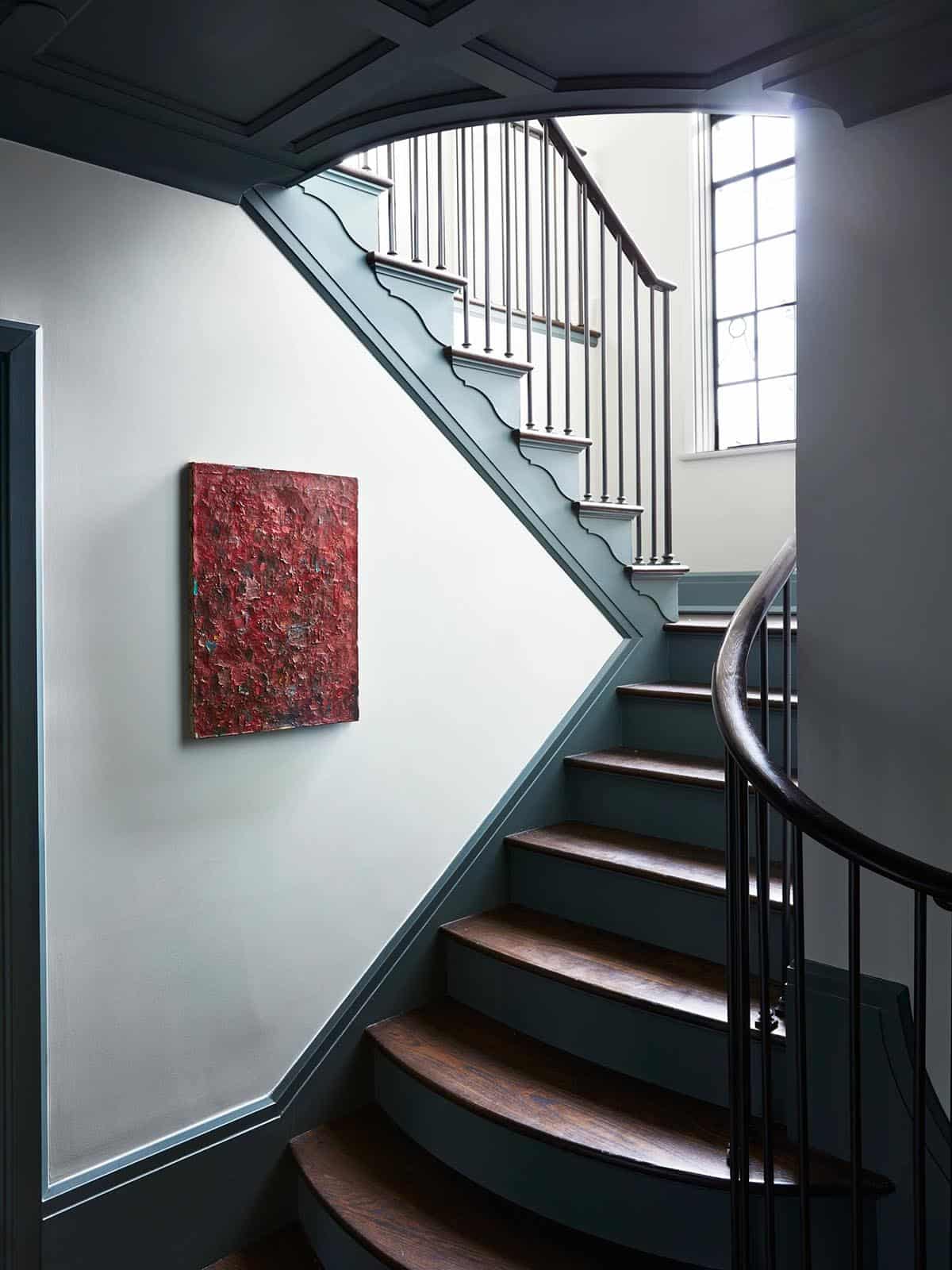 Curved staircase with blue-gray trim, wood treads and red abstract painting