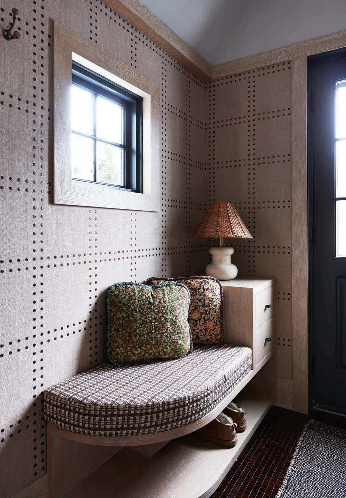 Mudroom bench with nailhead-patterned walls, plaid cushion and rattan lamp