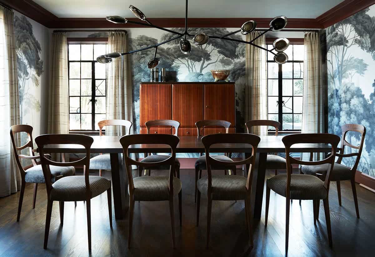 Dining room with tree mural wallpaper, branching chandelier and walnut chairs