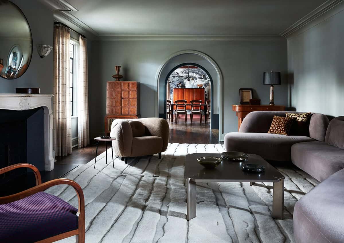 Living room with curved mauve sofa, bouclé armchair and carved wool rug