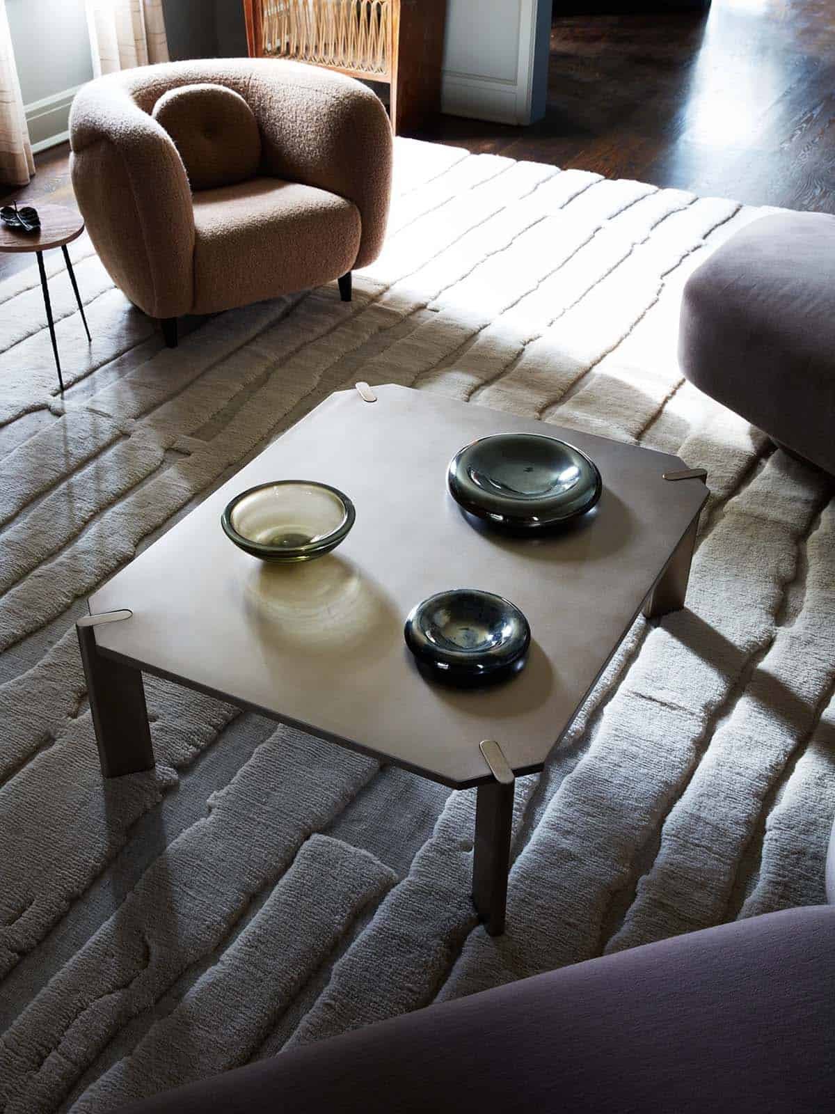 Steel coffee table with glass bowls on textured cream rug
