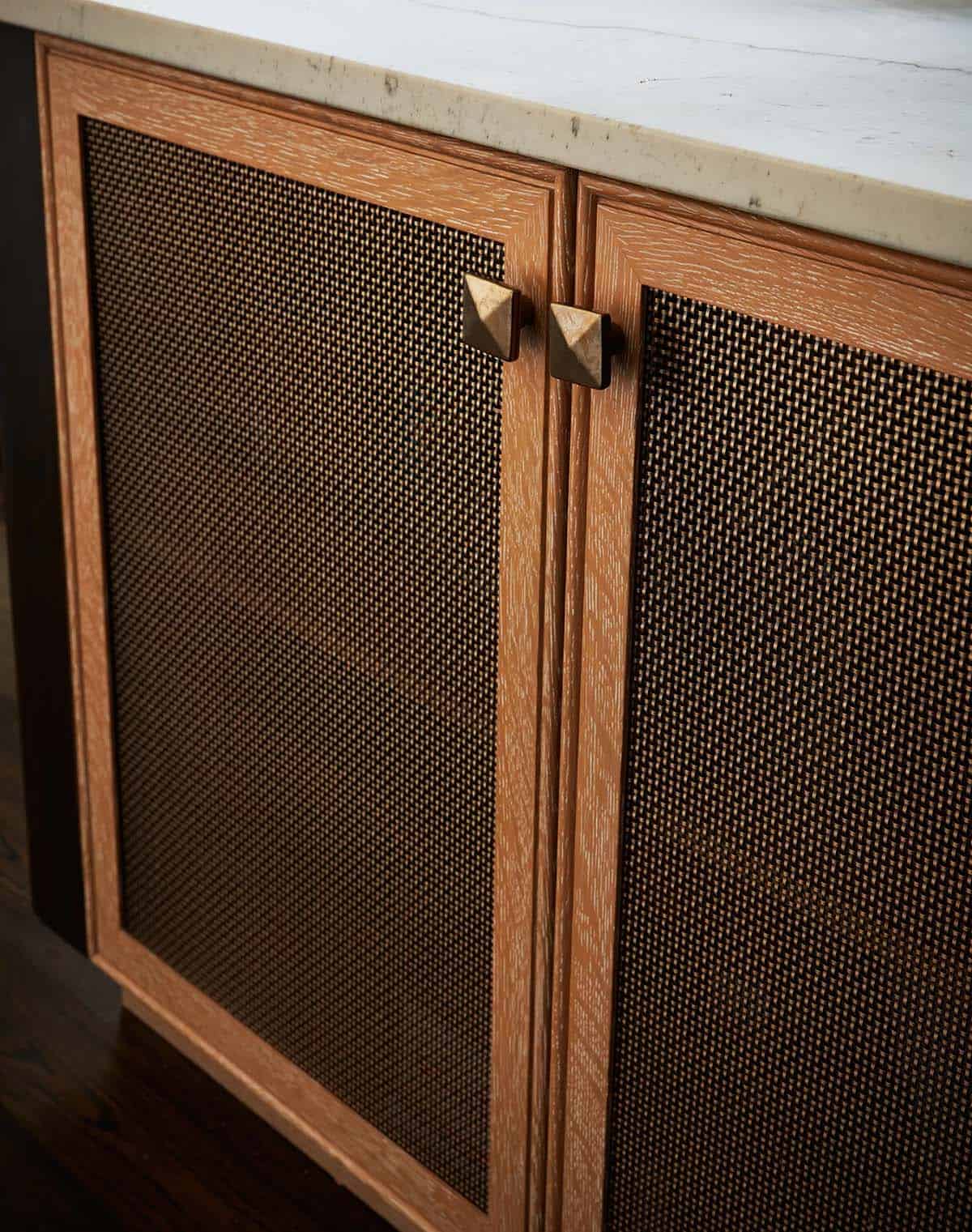 Cerused oak cabinet doors with woven metal mesh panels and pyramid knobs