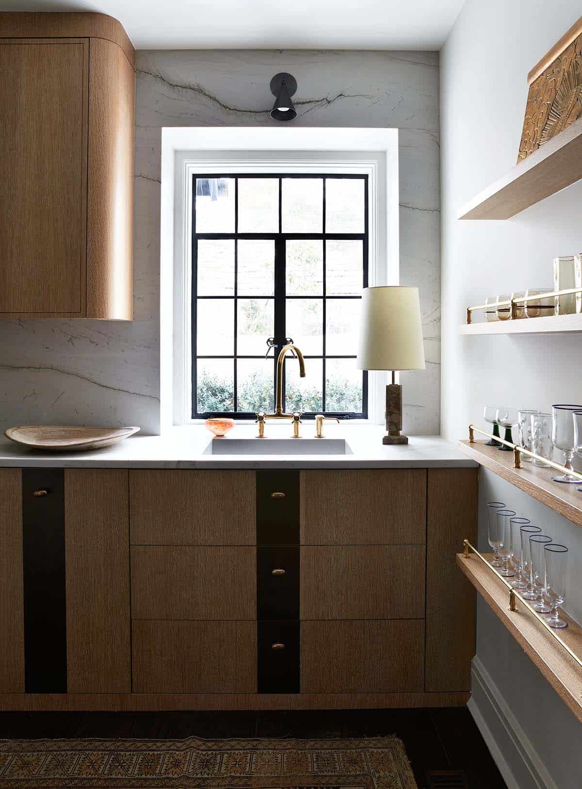 Butler's pantry with rounded oak cabinet, steel window and brass-railed shelves