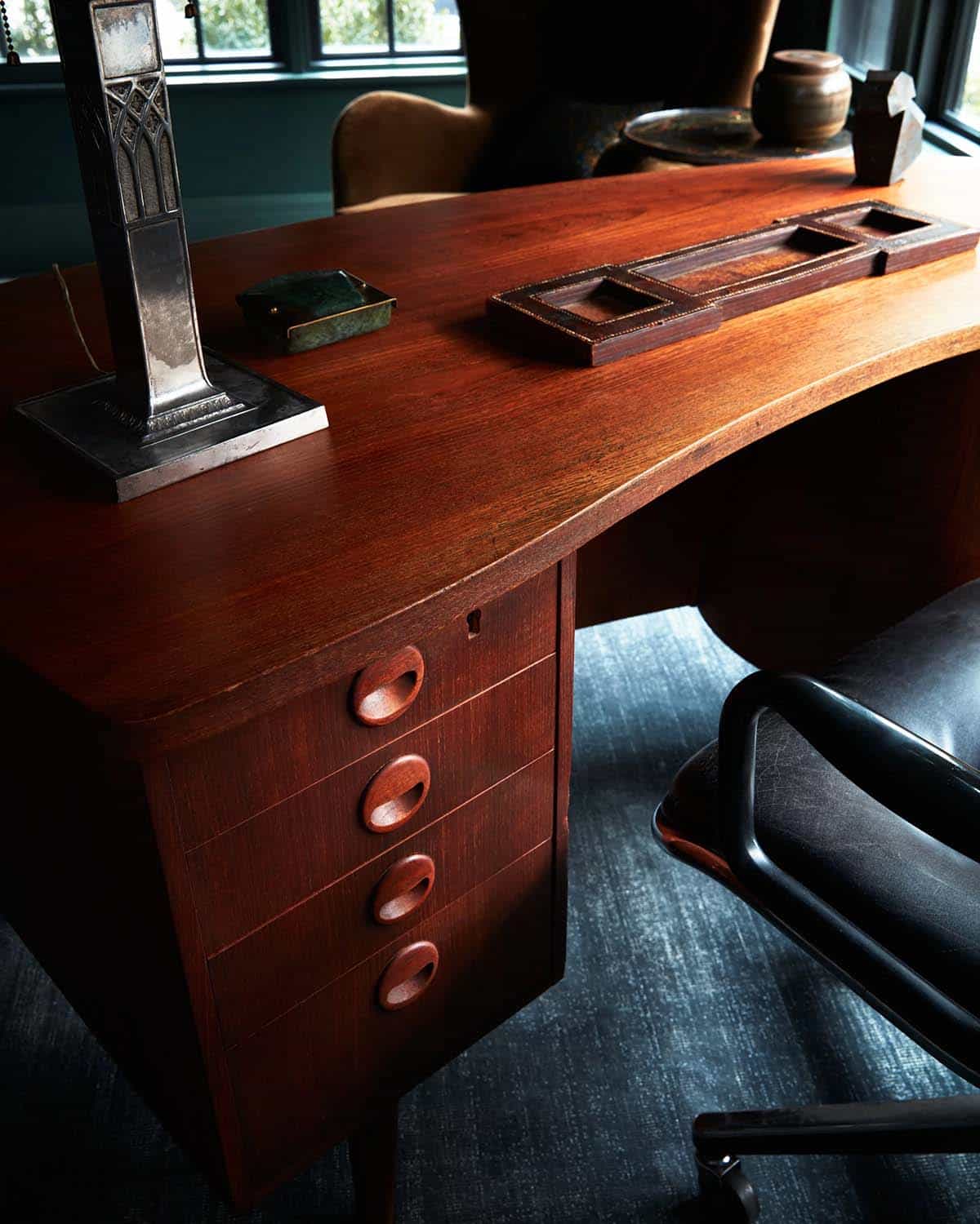 Teak desk with carved drawer pulls, pewter lamp and leather desk tray