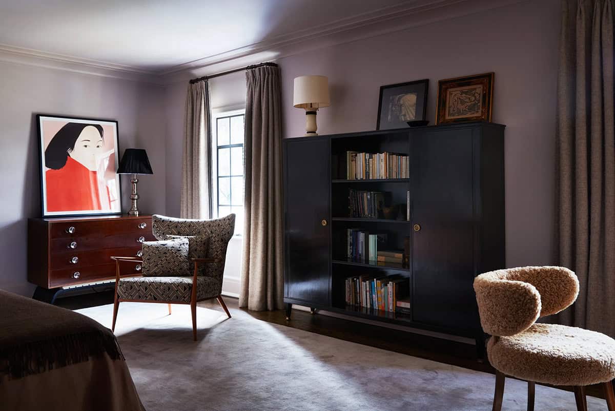 Primary bedroom with black bookcase, patterned armchair and shearling chair