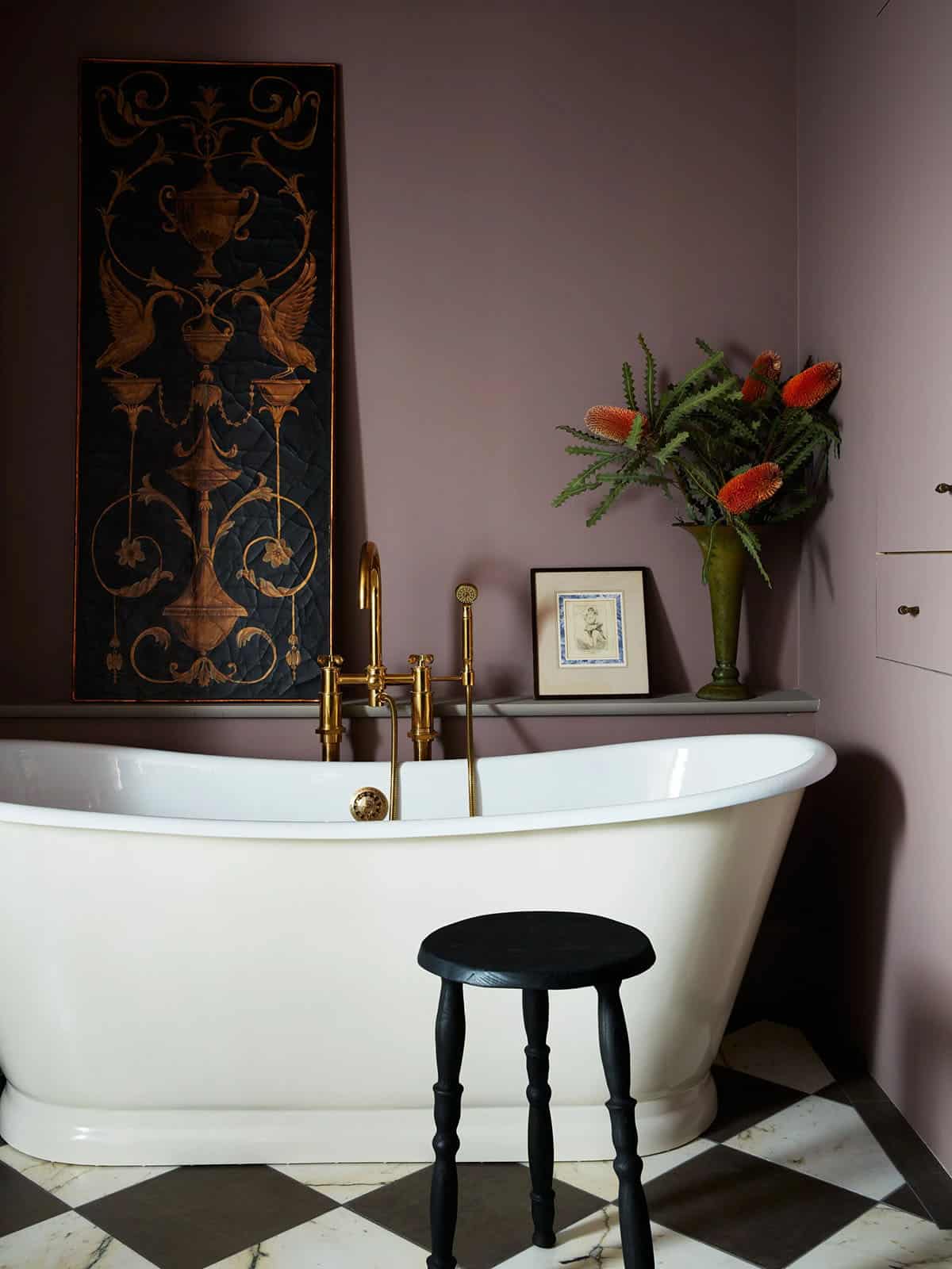Freestanding tub with brass filler beside a gilded antique panel