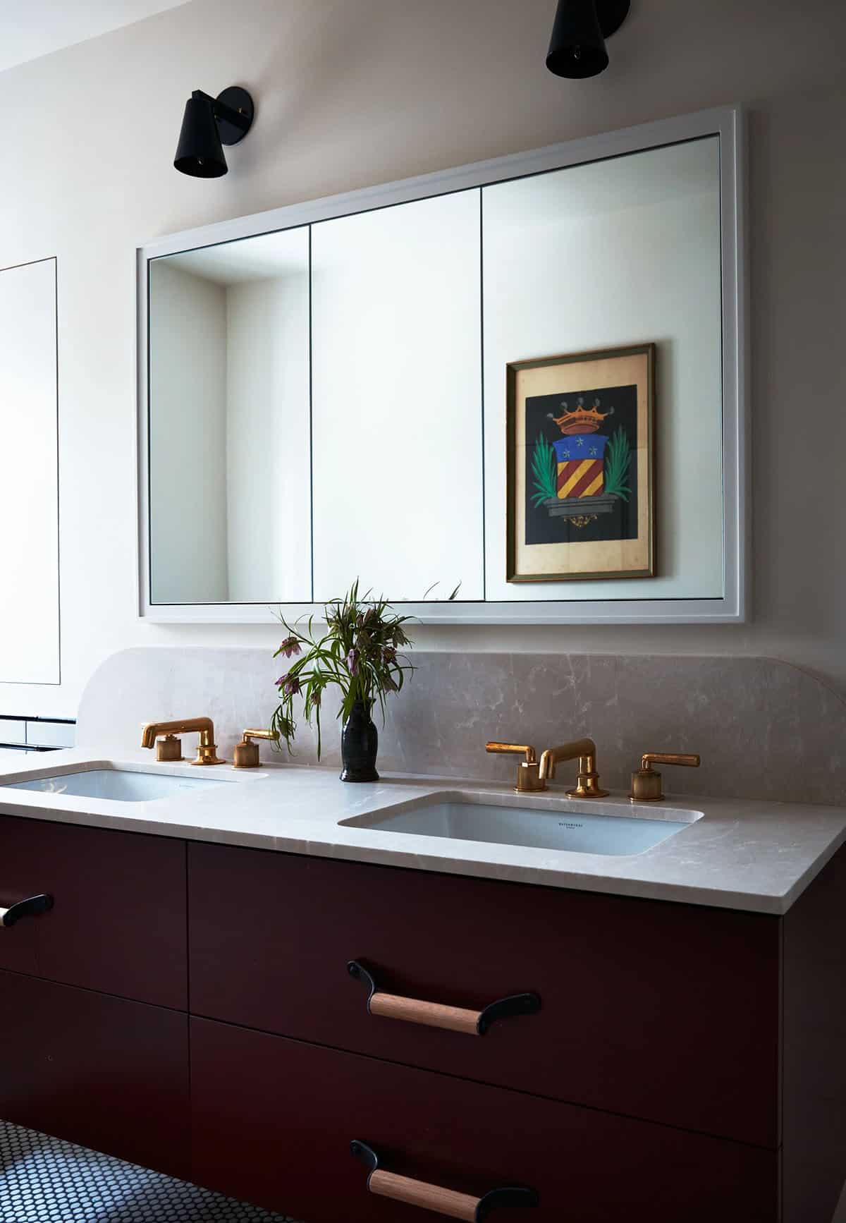 Bathroom with burgundy double vanity, brass faucets and framed crest